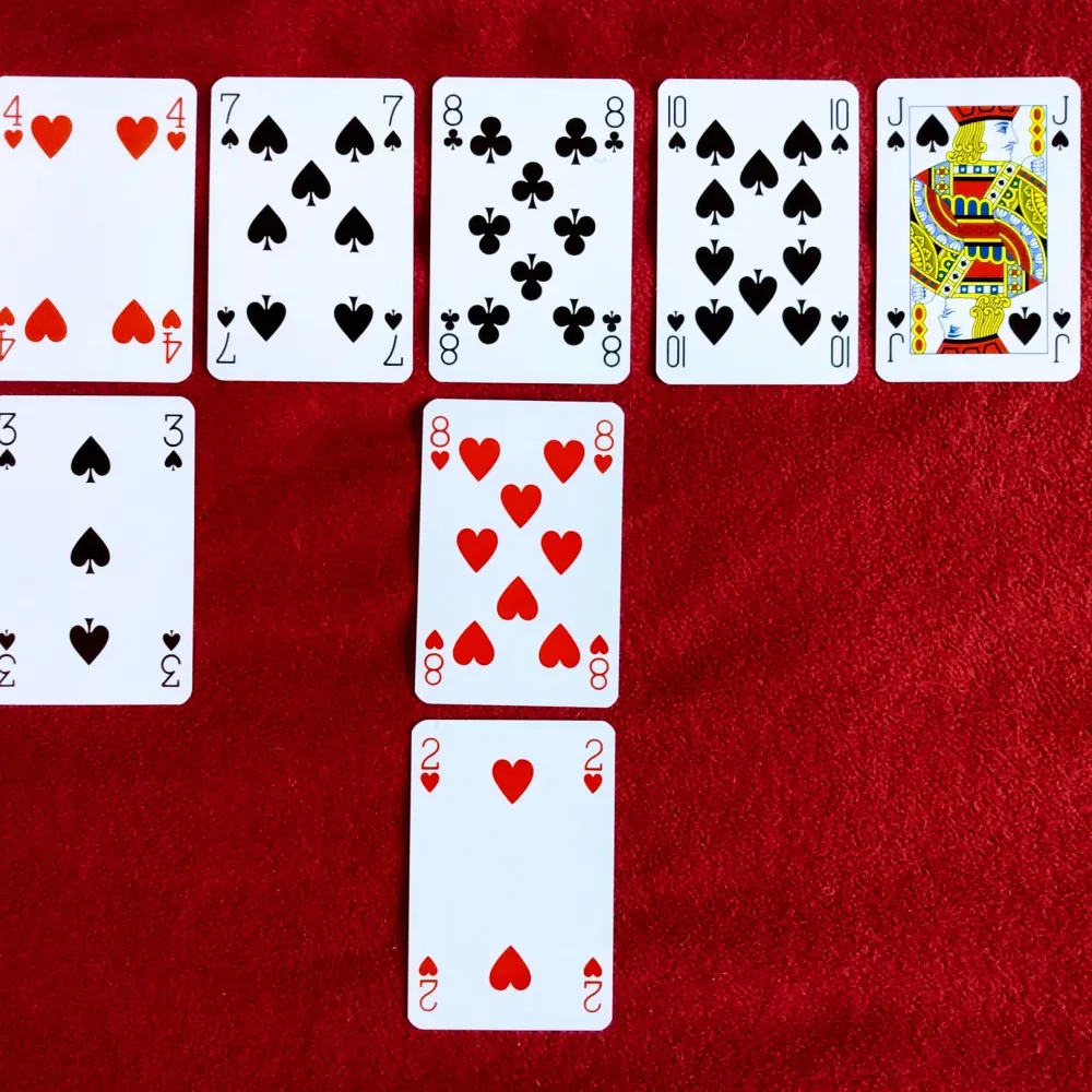 Playing cards laid out in rows on red felt